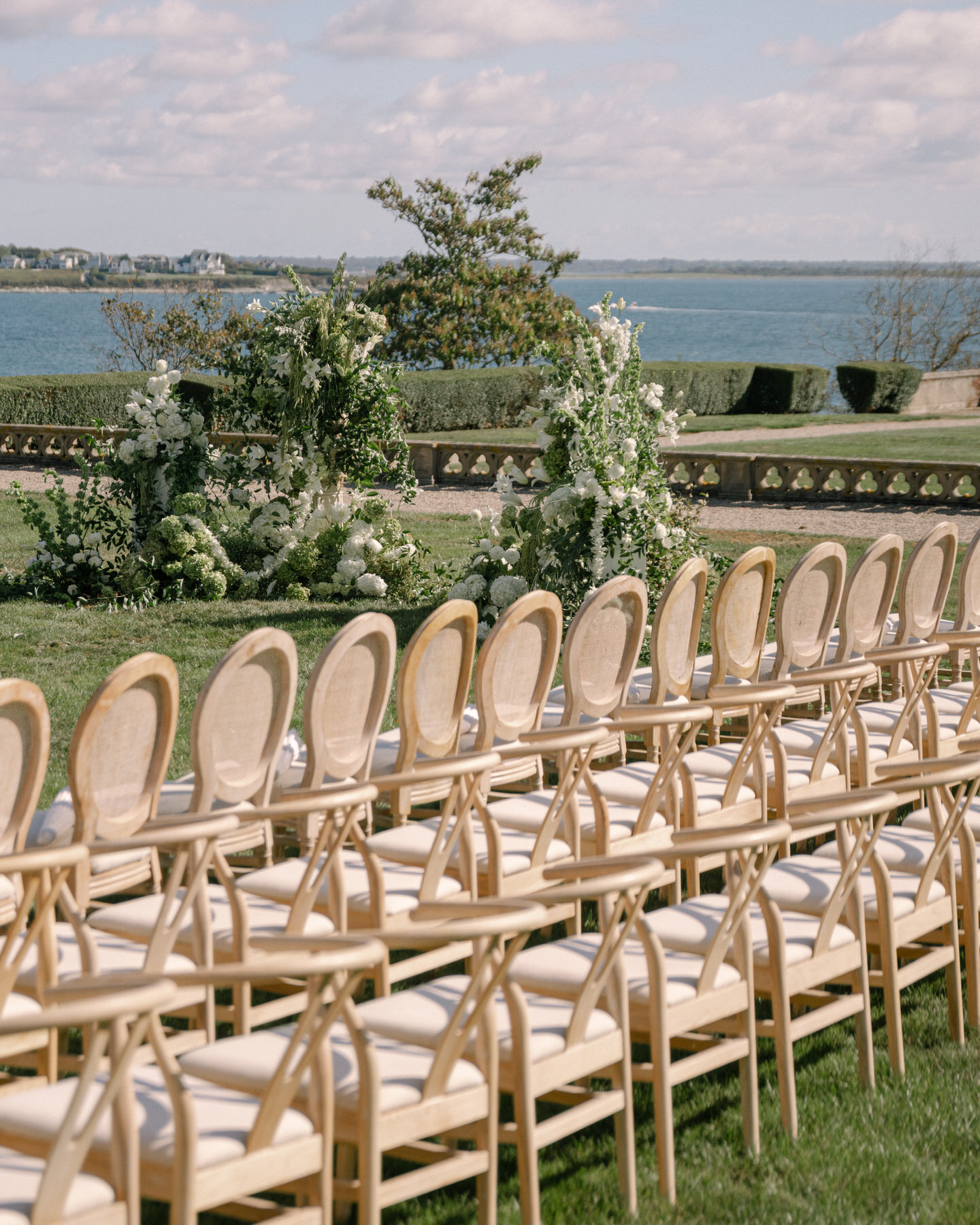 Elegant outdoor ceremony setup at the brunch wedding at Ochre Court Newport, with rows of chairs and a beautiful view of the water and lush greenery.