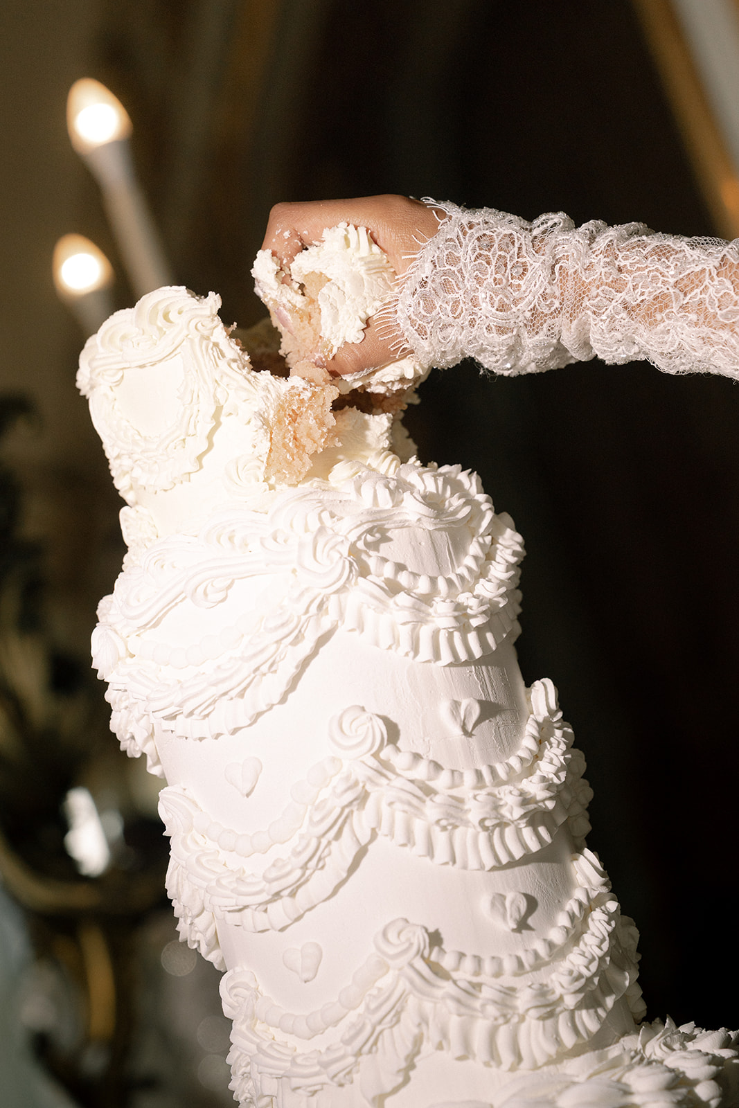 Close-up of the bride playfully breaking a piece of the intricately decorated wedding cake at their luxurious reception.