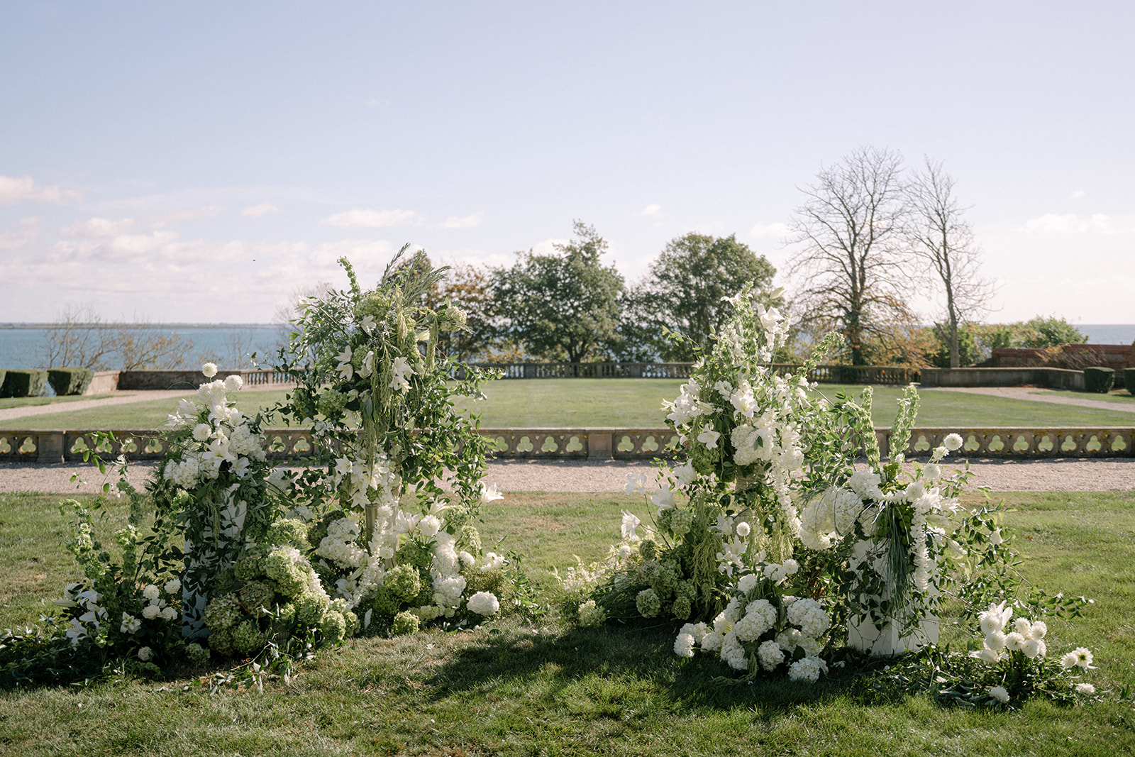Elegant floral arrangements set up at the outdoor ceremony for the brunch wedding at Ochre Court Newport, overlooking a beautiful landscape.