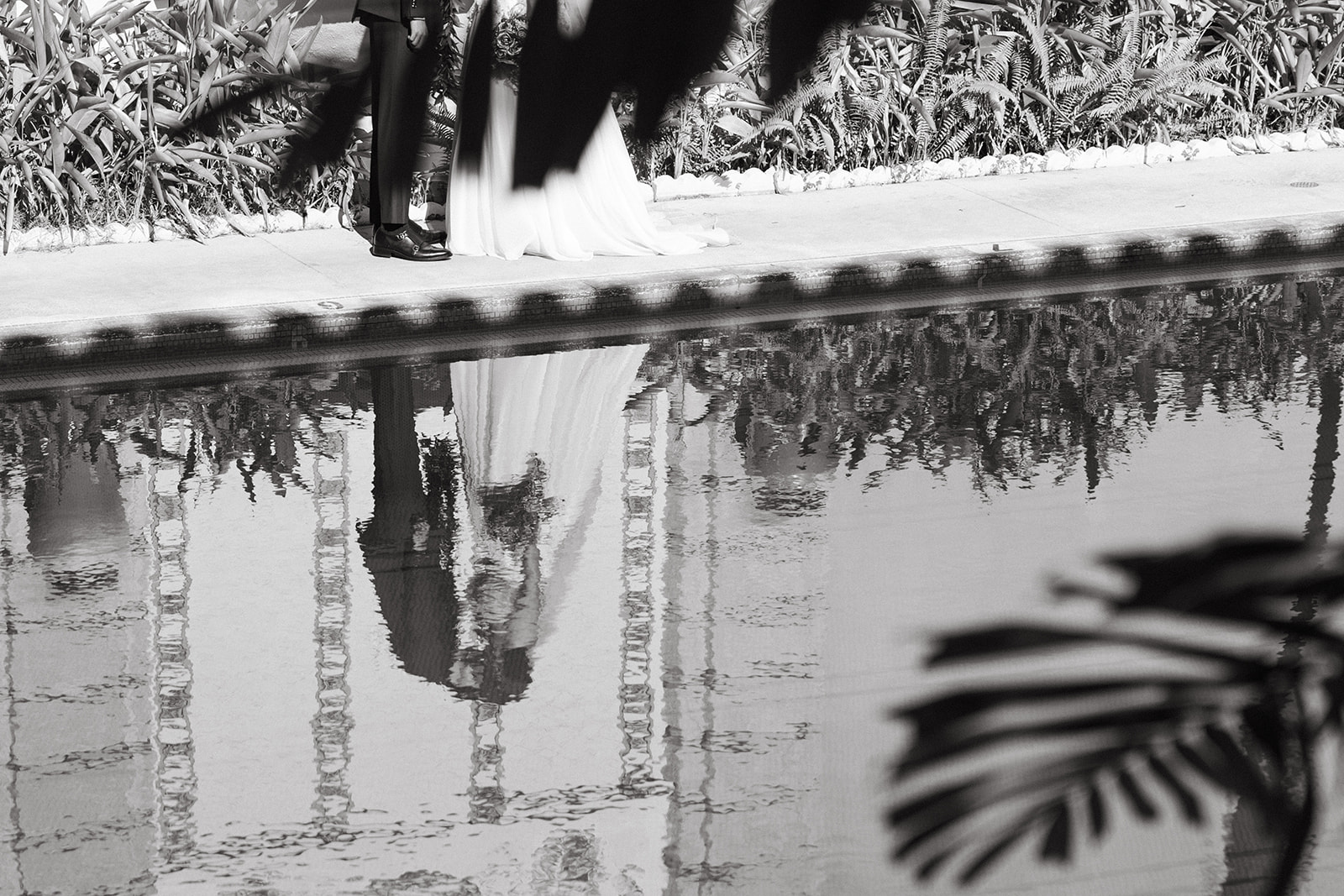 Artistic black-and-white reflection of newlyweds beside a pool at ʻIolani Palace in Honolulu.
