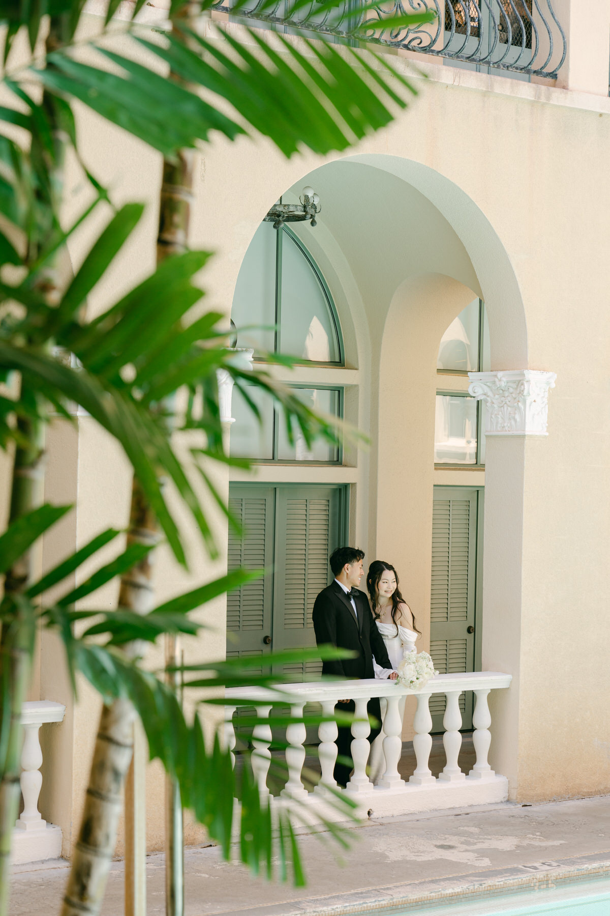 Newlyweds standing on an arched balcony before their Cafe Julia wedding reception.