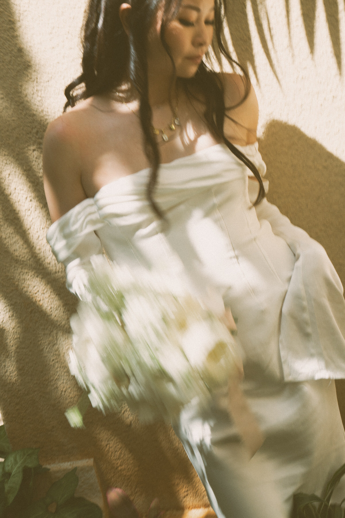 Bride holding a white floral bouquet in warm sunlight at her Cafe Julia wedding.