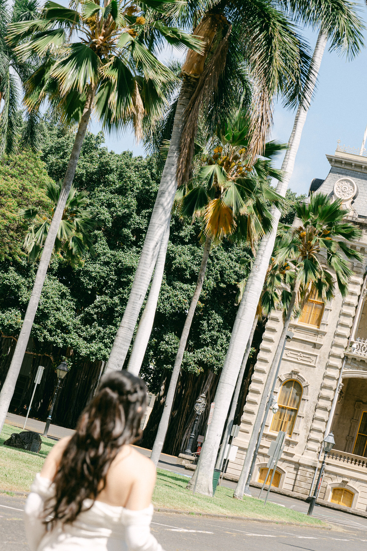 Bride walking beneath palm trees near Cafe Julia in downtown Honolulu.