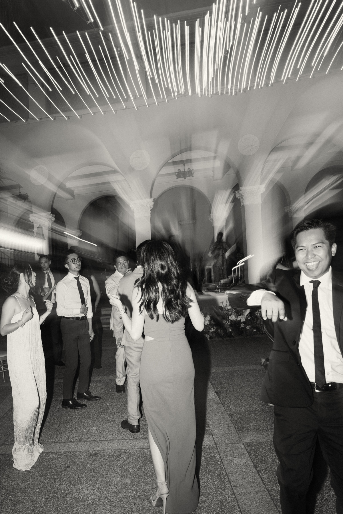 Bride dancing beneath string lights as guests watch at a Cafe Julia wedding reception.