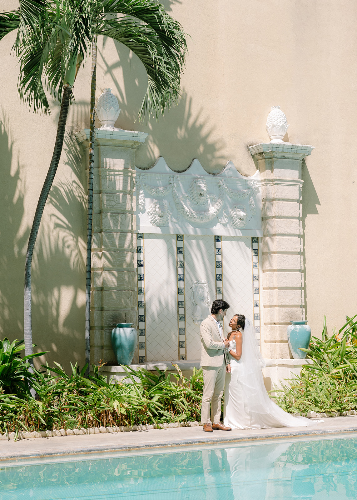 Newlyweds posing beside a turquoise pool before their Cafe Julia wedding celebration in Honolulu.