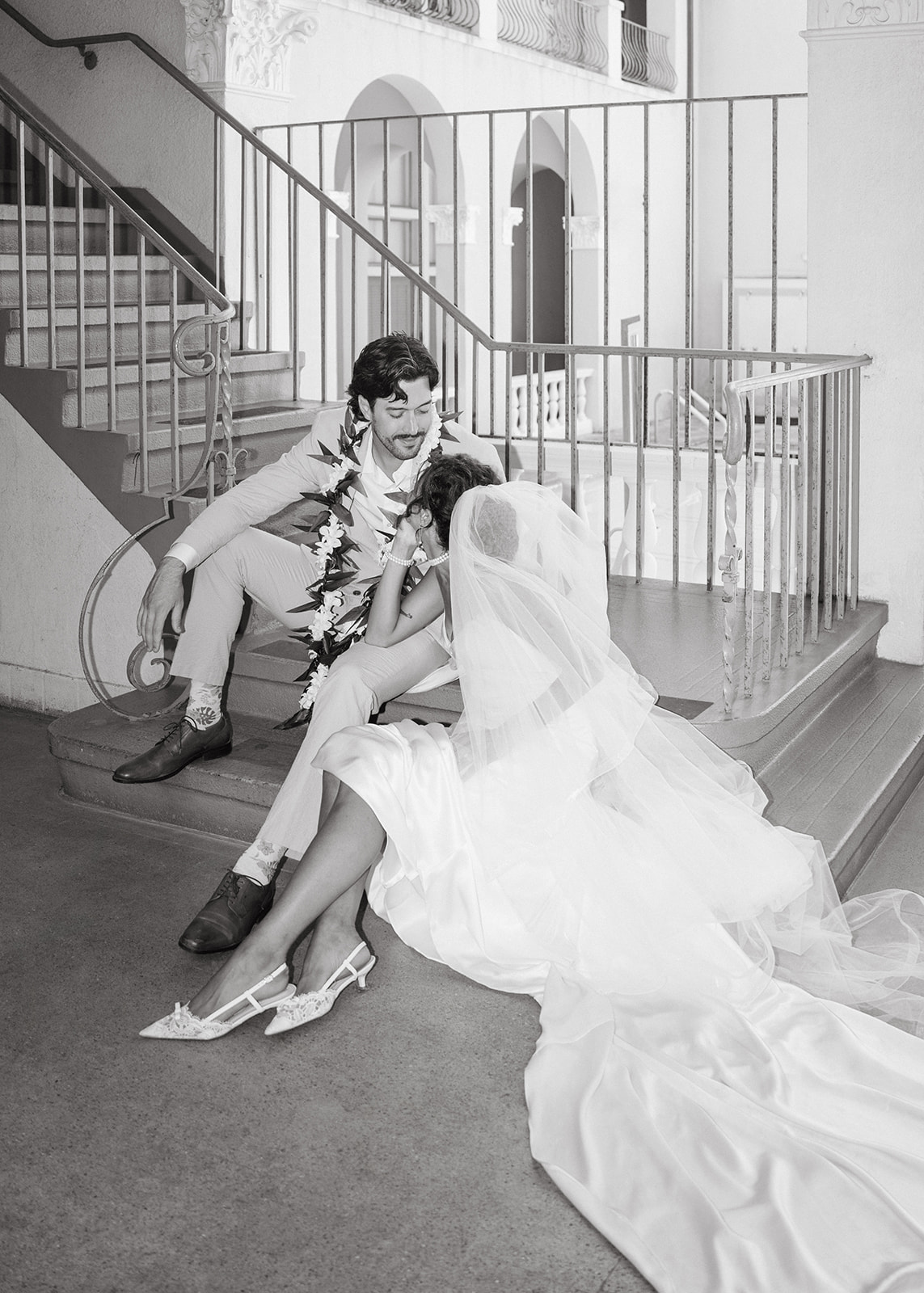 Newlyweds sitting together on a staircase during their Cafe Julia wedding in Honolulu.