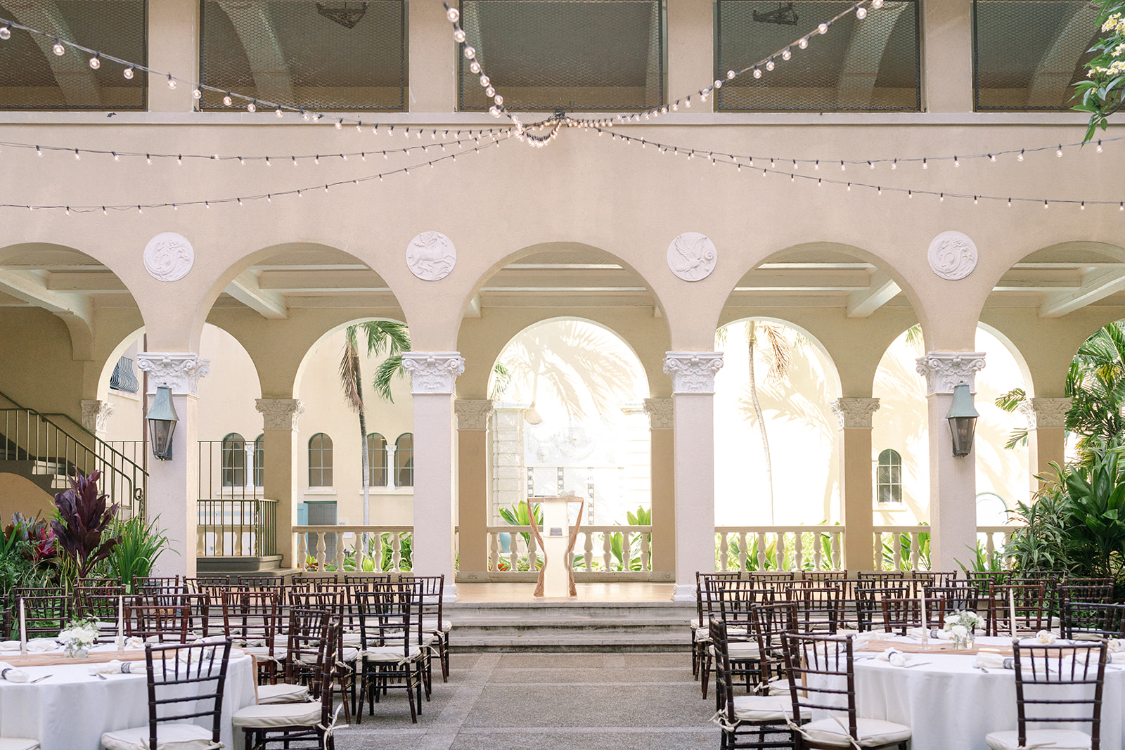 Courtyard ceremony seating and reception tables beneath string lights and arches at Cafe Julia.