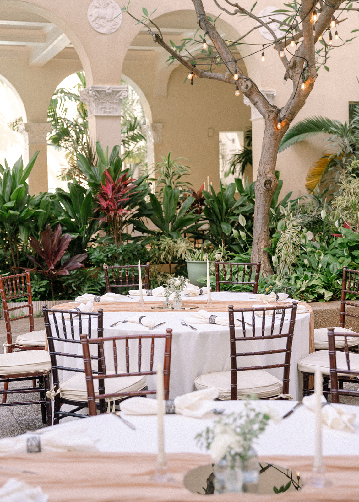 Wedding reception tables arranged among tropical greenery in the Cafe Julia courtyard.