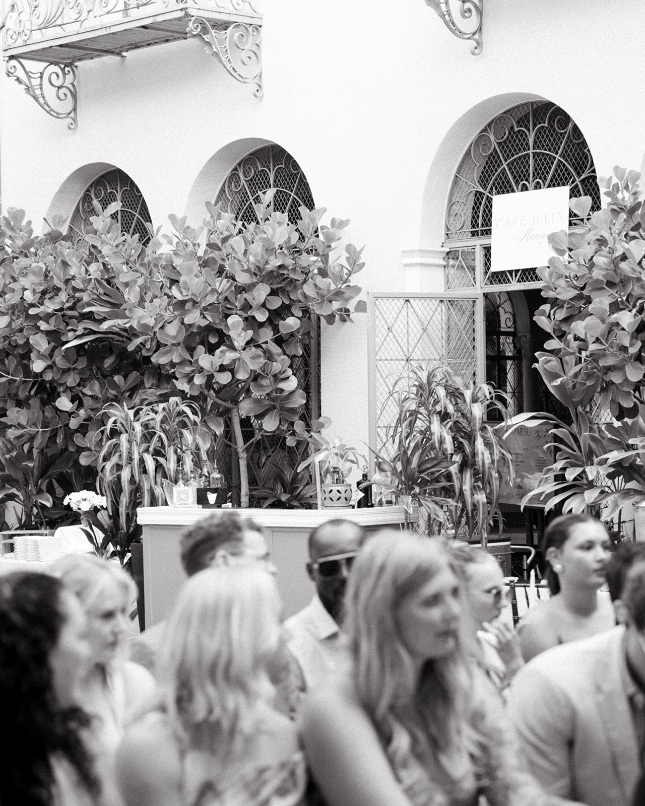 Guests seated at a floral courtyard reception during a Cafe Julia wedding in Honolulu.