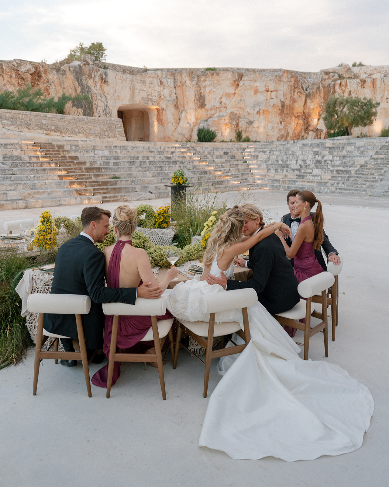 Bride, groom, and guests dine beside the tiered limestone amphitheatre at Cava Puglia.
