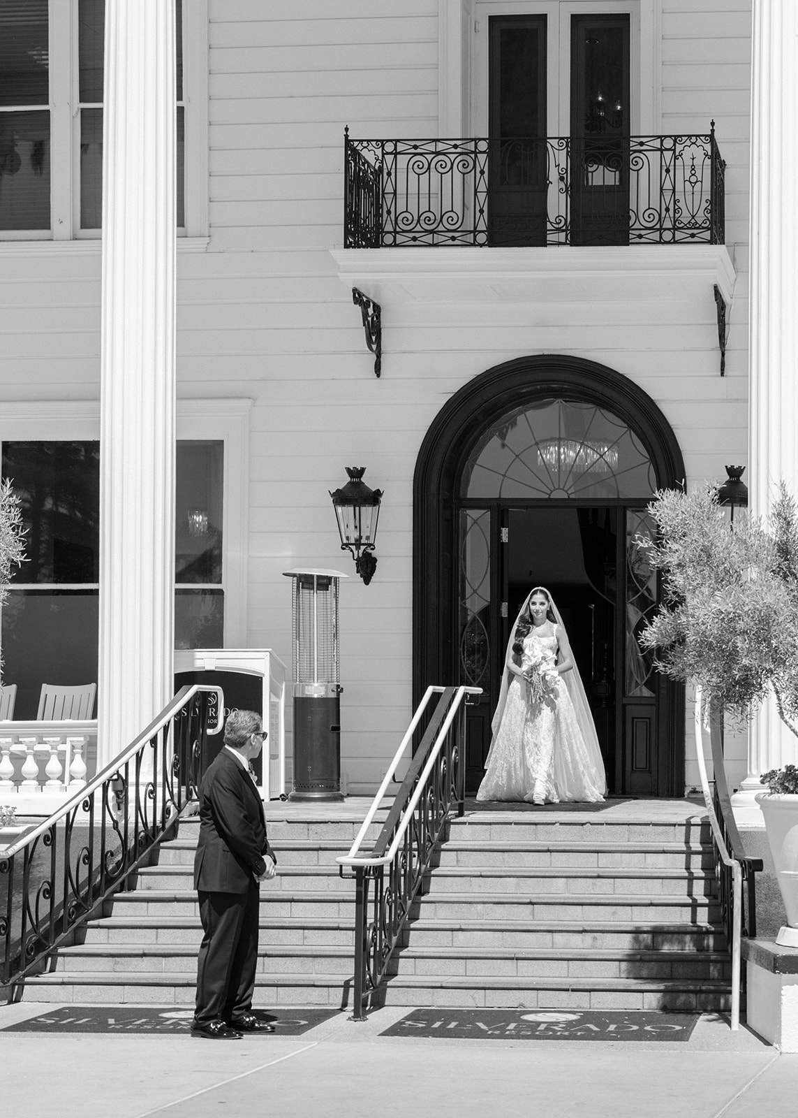 Bride stands in the arched entrance of the white mansion before her ceremony at Silverado Resort in Napa.