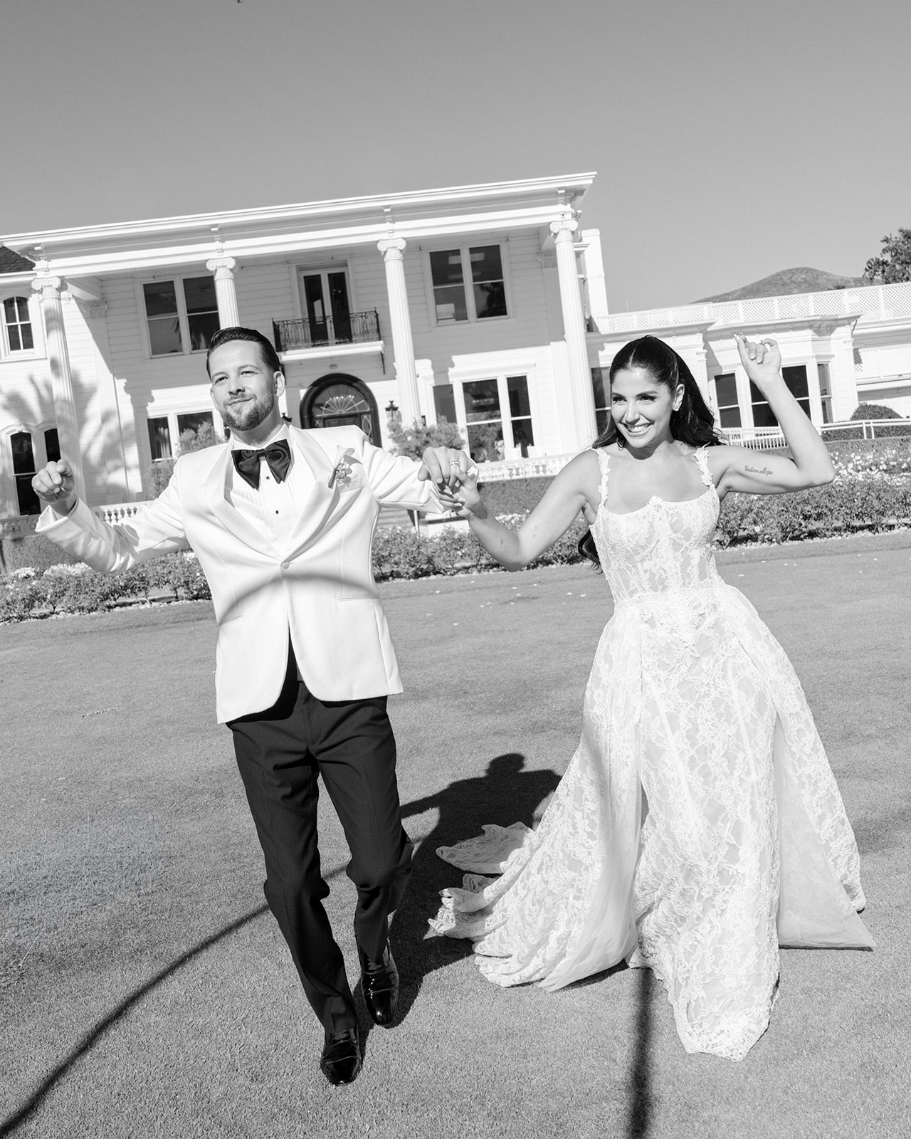 Bride and groom walk hand in hand outside the white mansion at Silverado Resort in Napa.