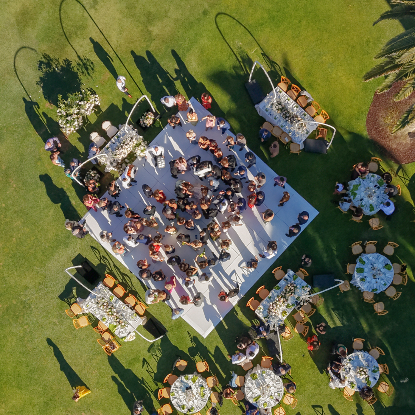 Aerial view of guests dancing on a white reception floor surrounded by outdoor dining tables at Silverado Resort in Napa.