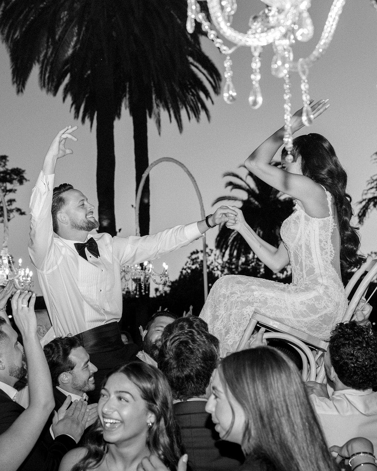 Bride is lifted on a chair as guests gather beneath crystal chandeliers at Silverado Resort in Napa.