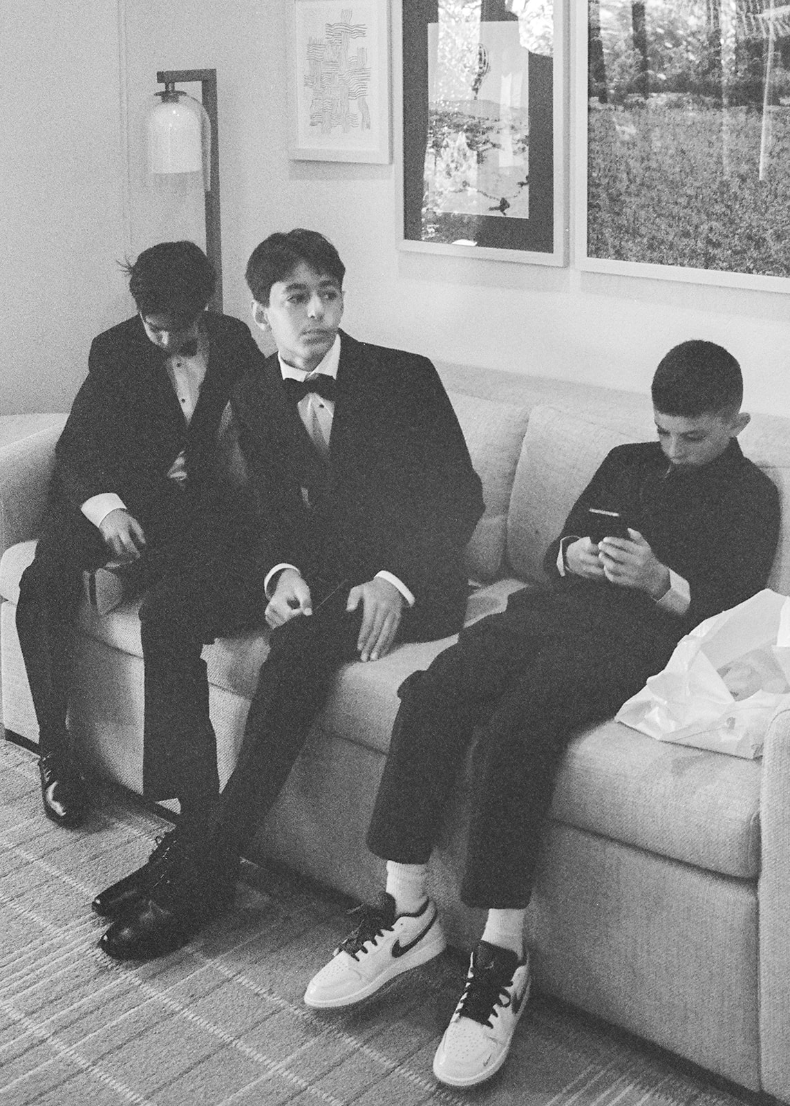 Three groomsmen sit on a sofa in black formalwear before the wedding at Silverado Resort in Napa.