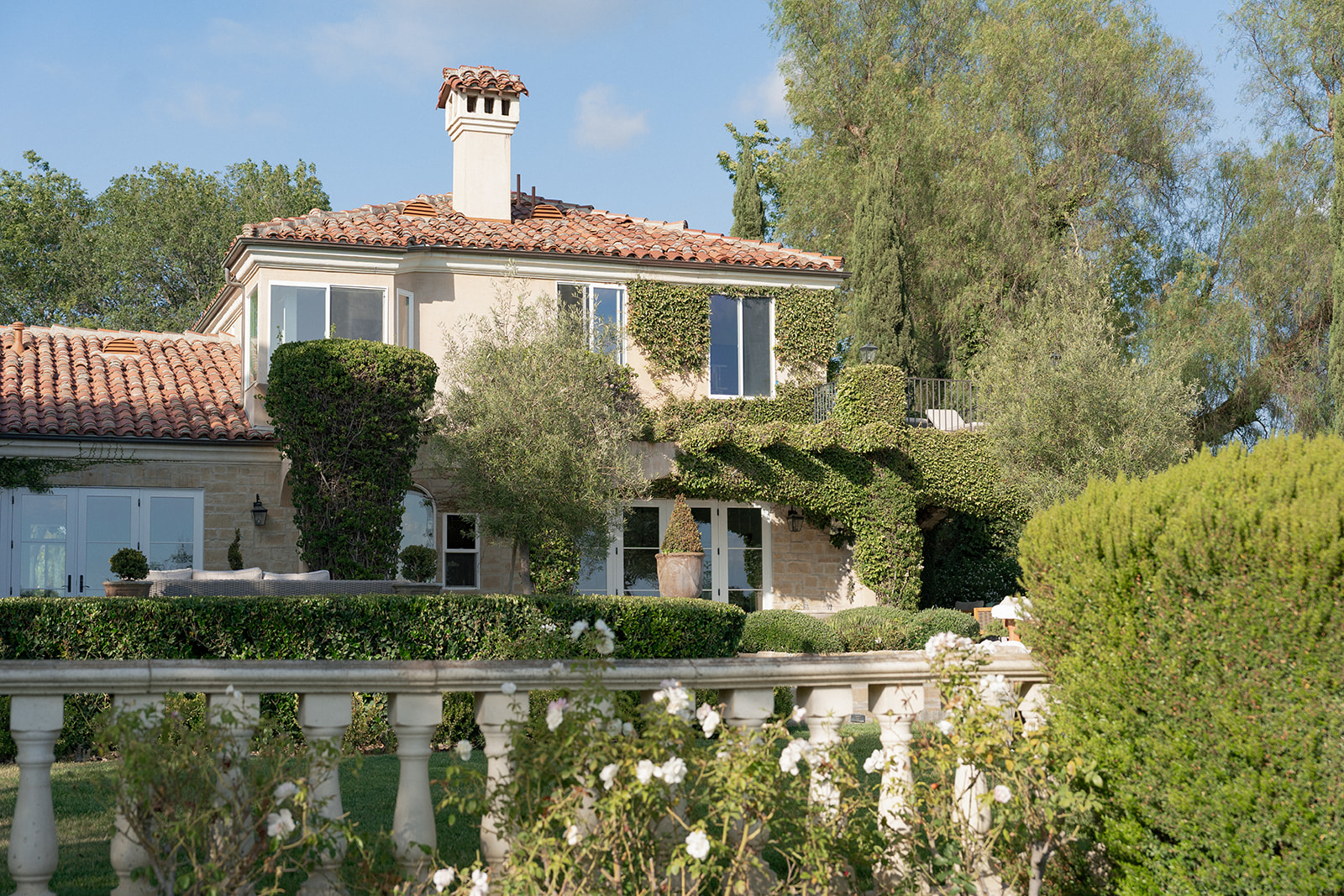 Villa Amodei’s ivy-covered exterior with terracotta roof tiles, garden greenery, and a stone balustrade.