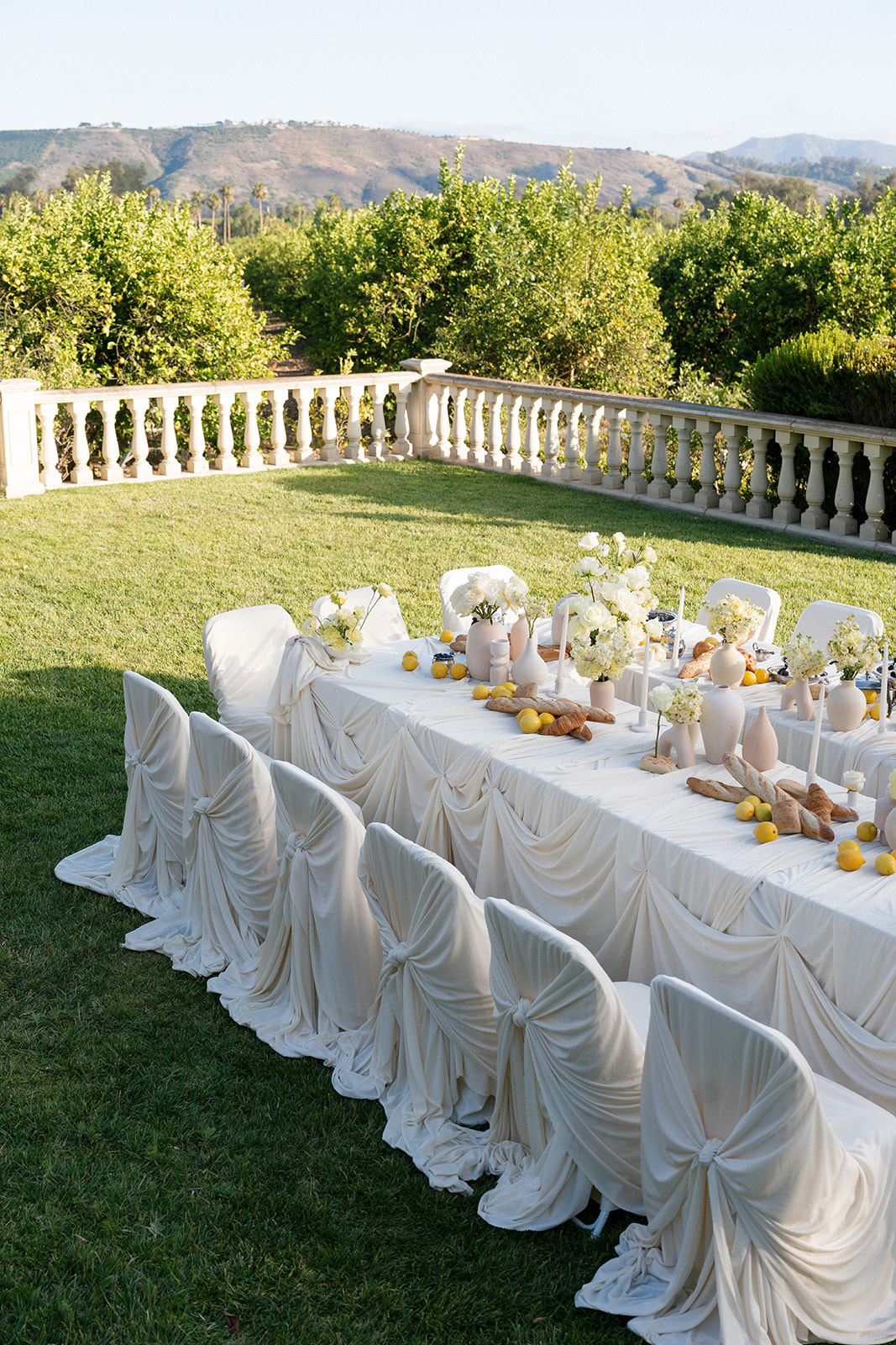 Outdoor wedding table at Villa Amodei with draped white linens, floral arrangements, and mountain views.