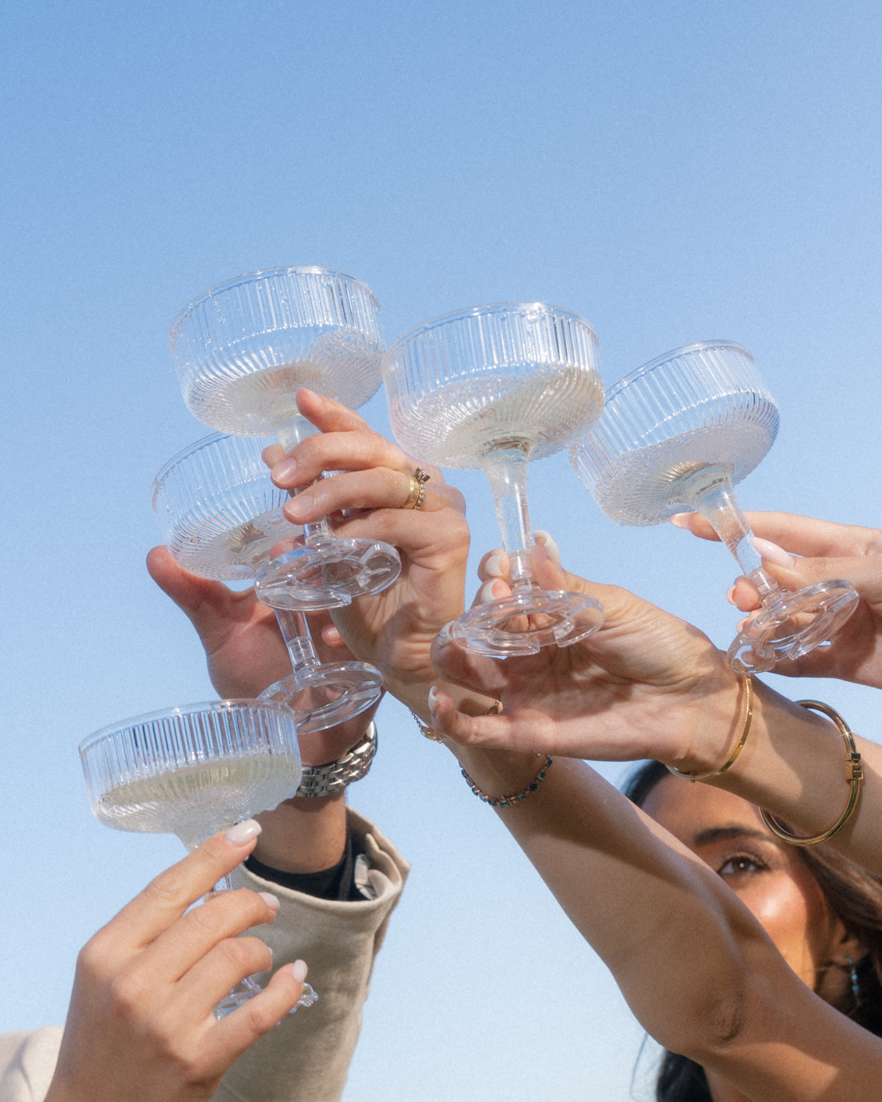 Wedding guests clink coupe glasses against a clear blue sky at Villa Amodei.